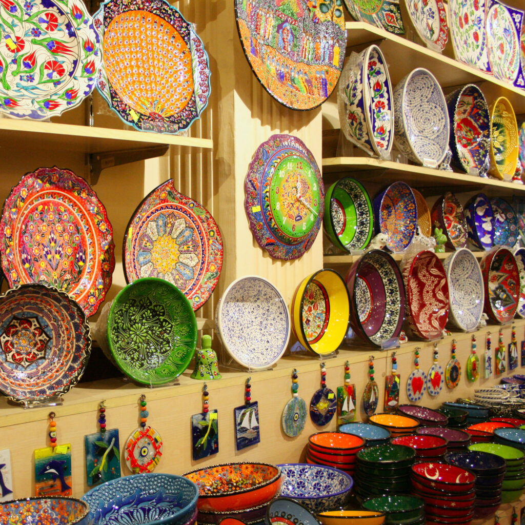 Shelves display colorful, intricately patterned ceramic plates and bowls, with small decorative tiles hanging below—inviting you to plan your luxury culinary or heritage trip to Morocco.